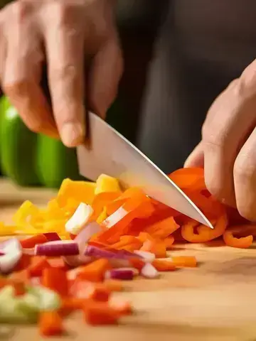 Knife slicing peppers on chopping board