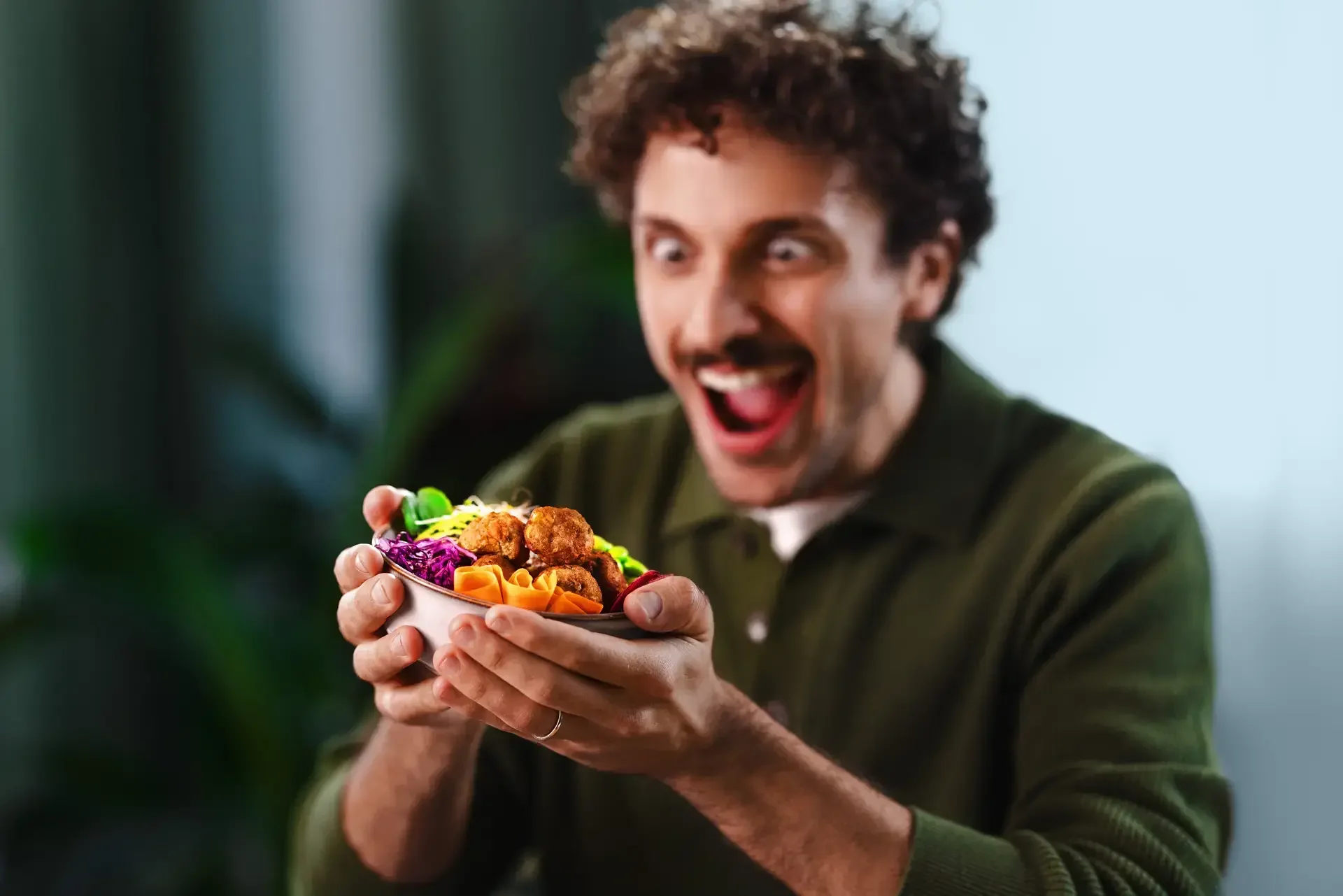 A man looking happily at the food he is holding on his hands.