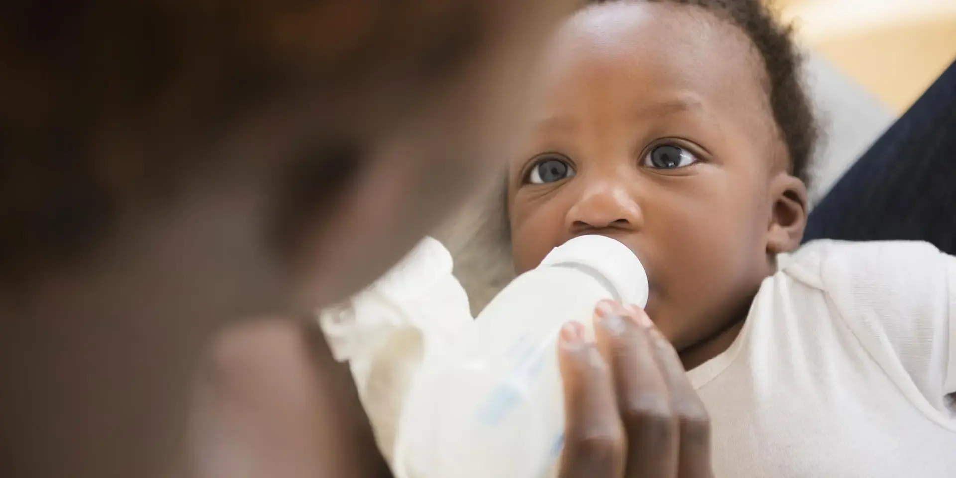 Une maman qui nourrit son bébé avec un biberon de lait Nidal