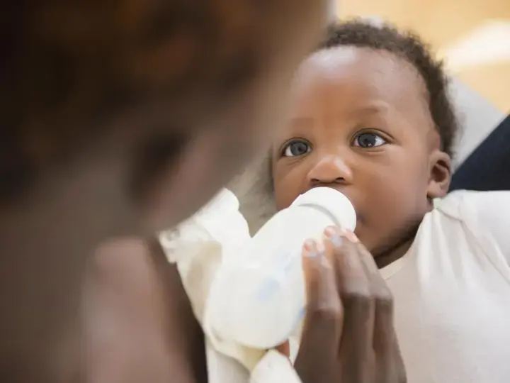 Une maman qui nourrit son bébé avec un biberon de lait Nidal